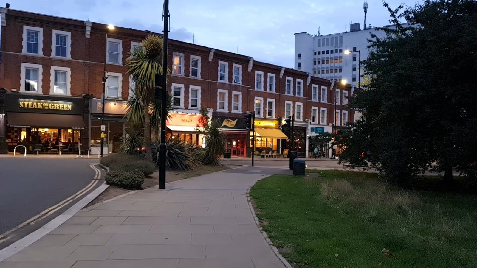 Lit shopfronts on a high street in Ealing, west London